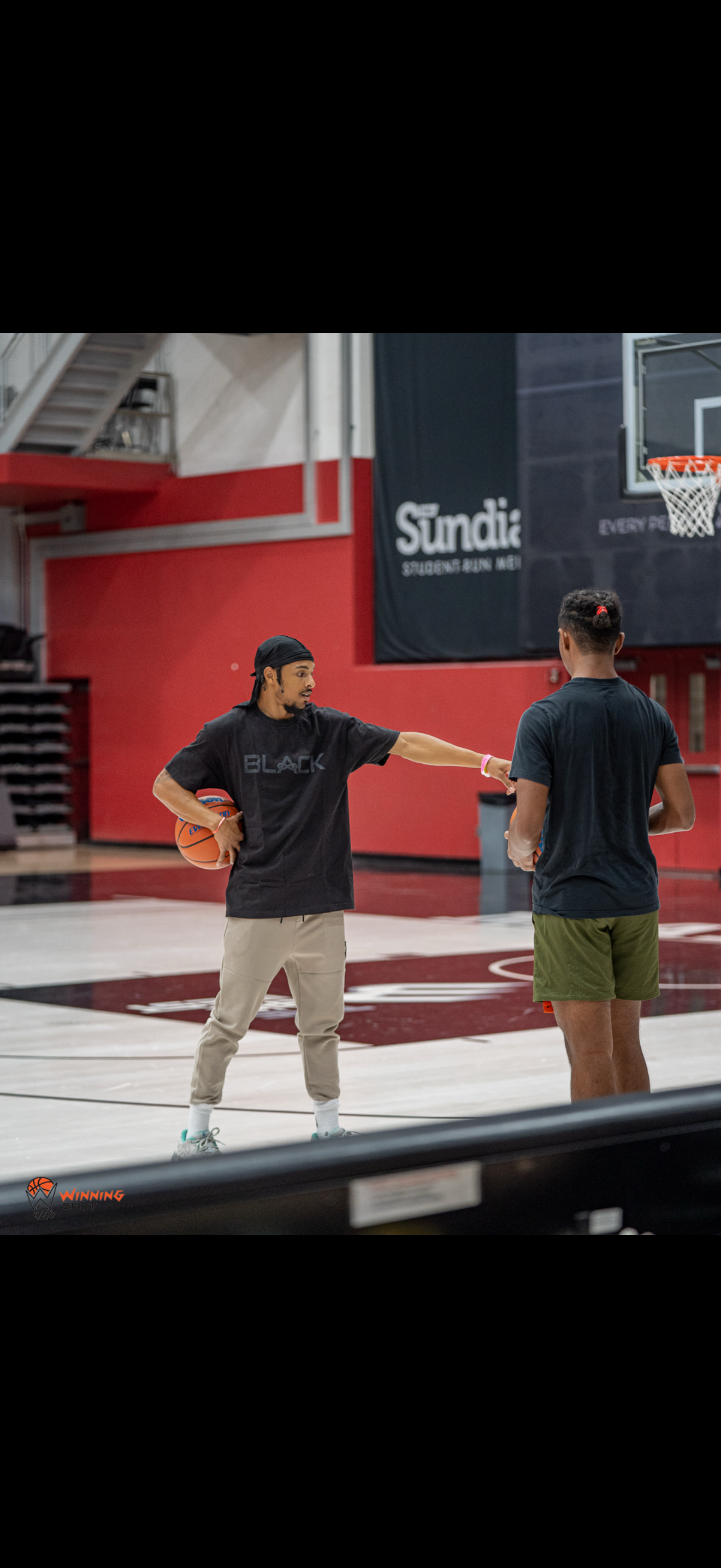 Andre Winn coaching an athlete through an on-court basketball drill.