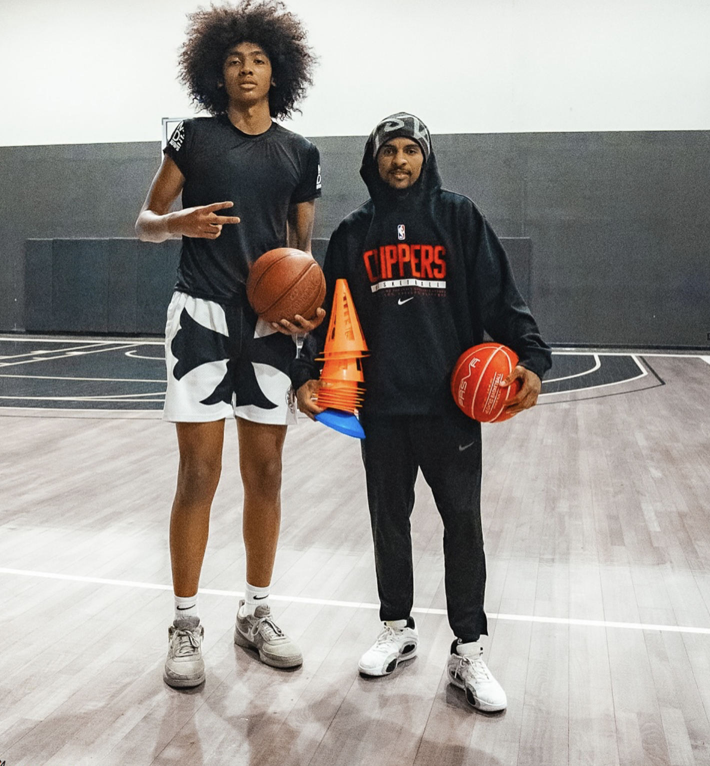 Basketball trainer posing with an athlete on the court